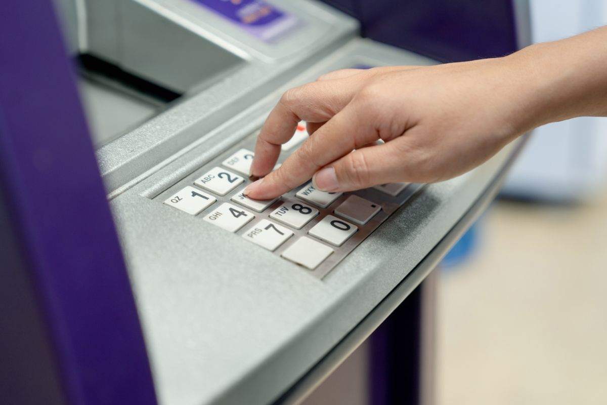 persona che preme sui tasti di un bancomat